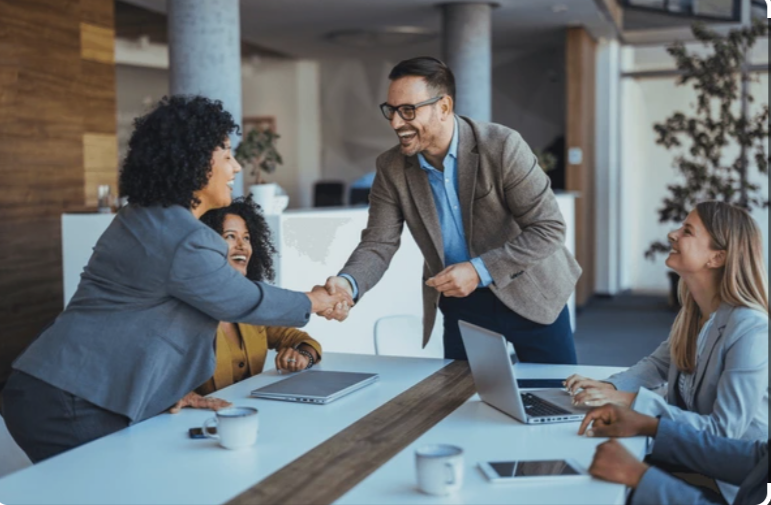 A team welcoming a colleague around a conference table